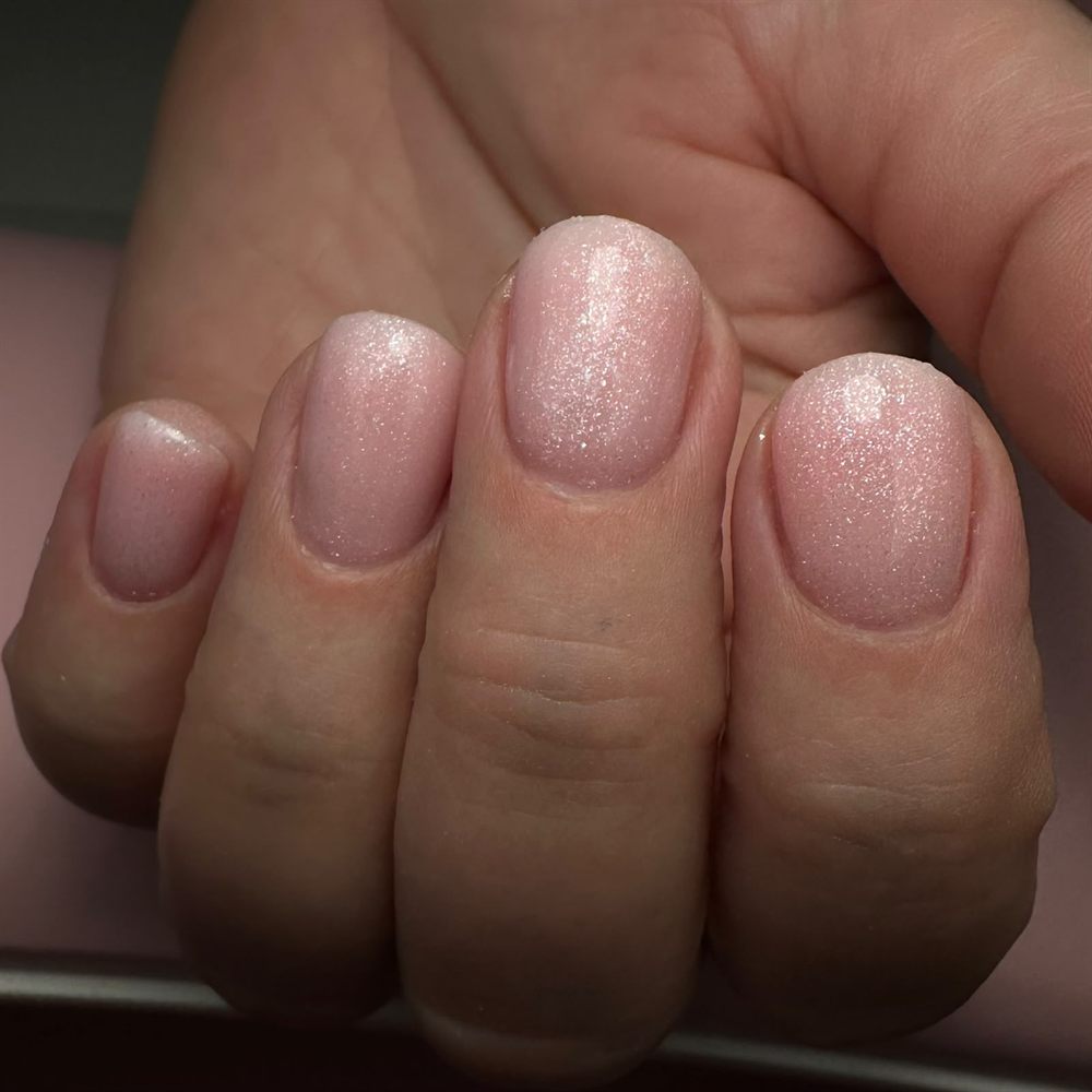 Korte, ronde nagels in een zacht roze met fijne glitter