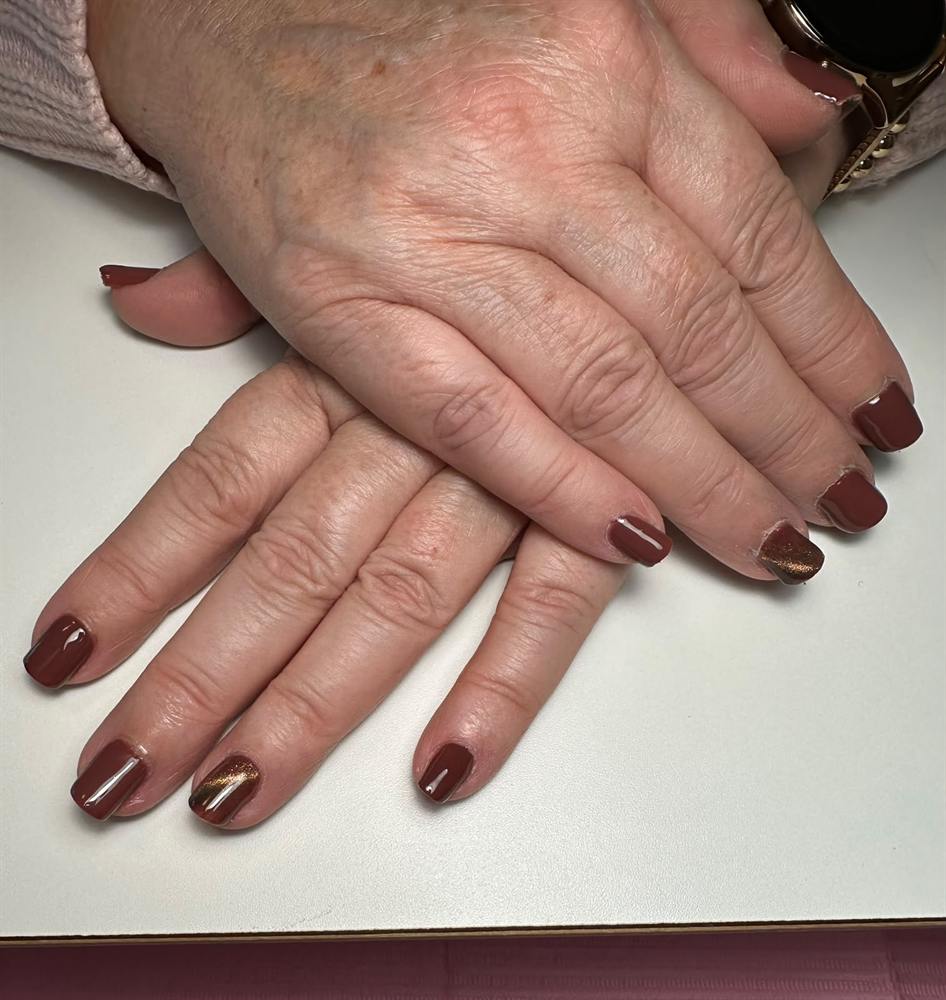 Korte nagels in terracotta met een koperkleurig accent
